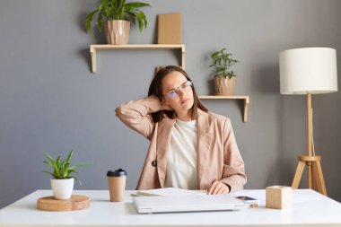 Genç, neşeli bir kadının iş yerinde kapalı bir defterle oturması, işini bitirmesi, boynunu ovması, yorgun ve bitkin düşmesi..