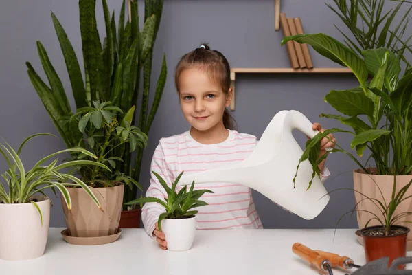 暗い髪の散水植物と少女の肖像画 屋内の花の世話をし 子供は温室内の彼女の母親の花屋を助け 散水缶を保持し カメラを見て — ストック写真