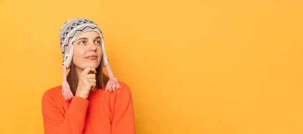 Innenaufnahme Einer Nachdenklichen Frau Mit Orangefarbenem Pullover Und Gestricktem Ohrenklappenhut — Stockfoto