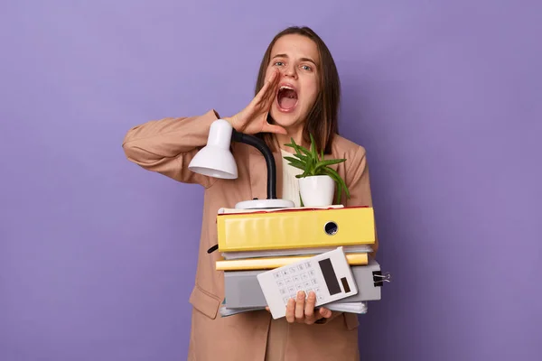 Image of beautiful young adult woman wearing beige jacket holding lot of documents folders isolated over lilac background, screaming loud, making announcement,