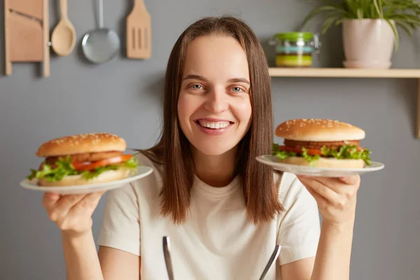 Приміщенні Посміхається Весела Кавказька Жінка Двома Смачними Свіжими Гамбургерами Сидять — стокове фото