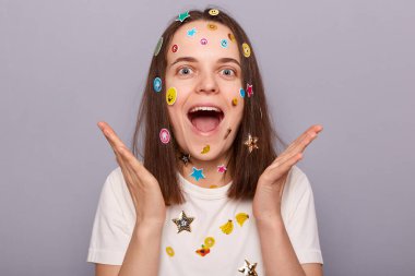 Gri arka planda izole edilmiş komik çıkartmalarla kaplı heyecanlı neşeli bir kadının kapalı çekimleri. Mutlulukla bağırıyorlar. Keyifli olmak, harika haberler duymak..