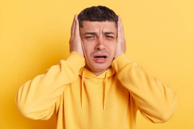 Üzücü üzgün kapüşonlu adam kendini kötü hissediyor. Ellerini başının üstünde tutuyor. Gürültülü sesler duyuyor..