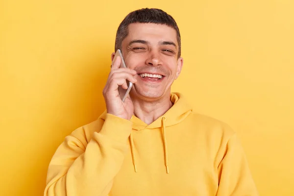 穿着休闲装的男人笑着在手机上说着笑着听笑话看着镜头在黄色背景上显得孤立无援 — 图库照片