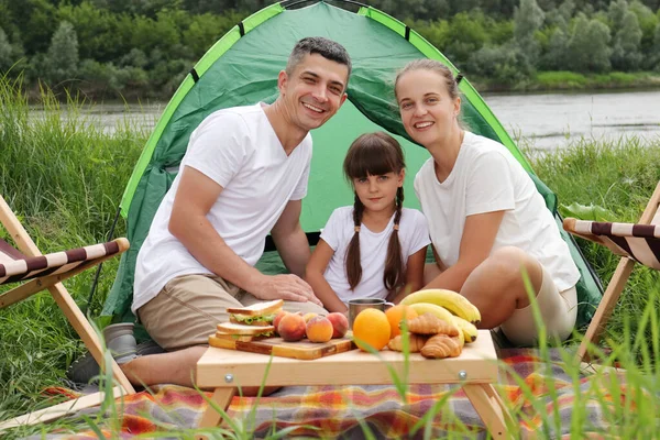 快乐的一家人坐在地上的帐篷旁野餐 享用美味的水果和三明治 在露天度过快乐的周末 — 图库照片