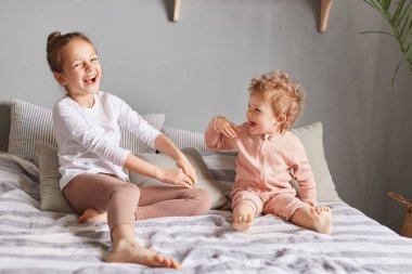 Son derece mutlu küçük kızlar yatak odasında oynuyorlar, yüksek sesle gülüyorlar, neşeli bir ruh hali içindeler, ev kıyafetleri giyiyorlar, hafta sonu uyanıp eğleniyorlar..