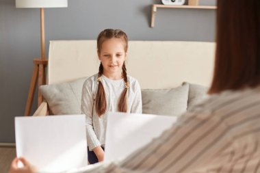 Doktor psikolog küçük bir hastayla test yapıyor, küçük kız resimlere bakıyor psikoterapist danışmanlığı akıl sağlığı sorunlarını çözüyor..