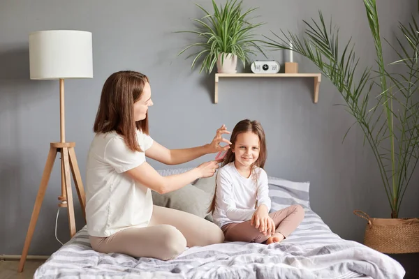 Young Mother Making Hairstyle Her Daughter Sitting Bed Bedroom Combing — Stock Photo, Image