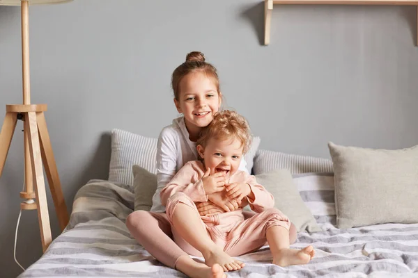 Positive Adorable Cute Happy Little Girls Playing Bedroom Sitting Bed — Stock Photo, Image