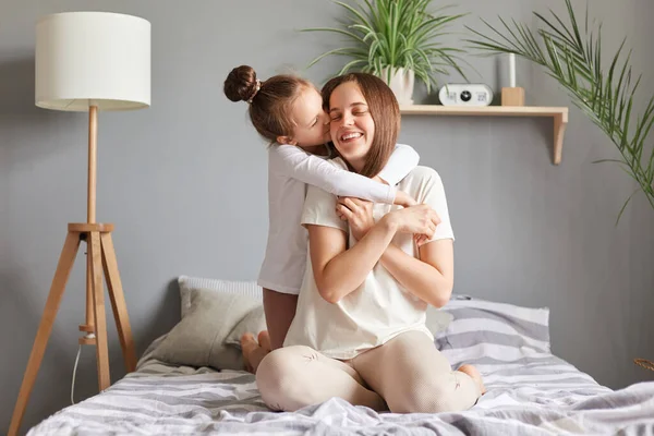 Cute Charming Kid Kissing Hugging Mother Daughter Mom Sitting Bed — Stock Photo, Image