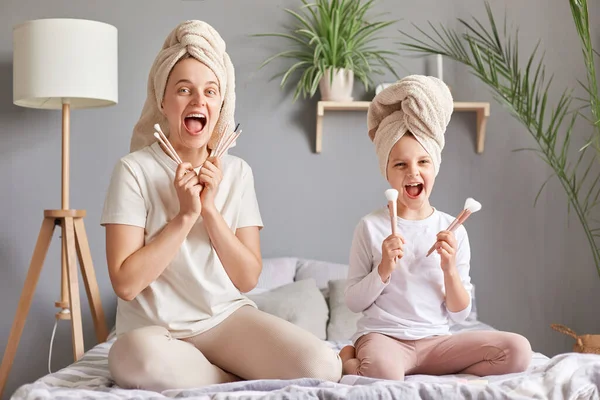 Joyful Screaming Mother Daughter Towels Bed Holding Powder Brushes Yelling — Stock Photo, Image