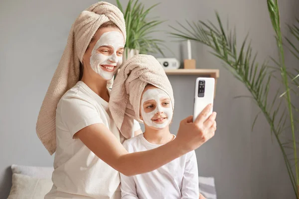 Portret Uśmiechniętej Matki Jej Córeczki Maskach Ręcznikach Robienia Selfie Podczas — Zdjęcie stockowe