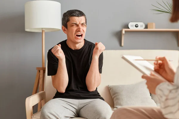 Angry Aggressive Young Man Black Shirt Sitting Sofa Psychologist Office — Stock Photo, Image