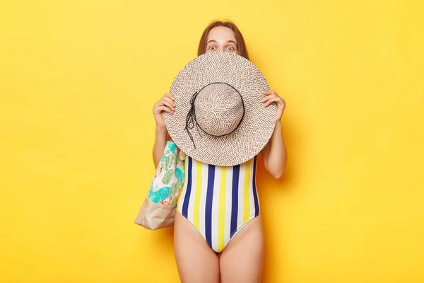 在暑假里 穿着条纹泳衣的害羞女人把脸藏在草帽后面 提着袋子 — 图库照片