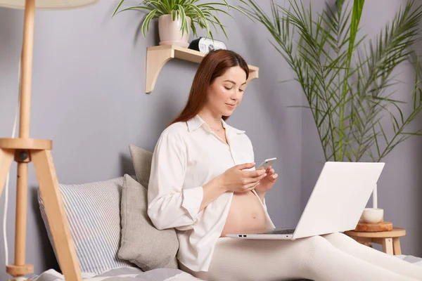 Mujer Embarazada Cabello Castaño Sentada Cama Usando Computadora Casa Marcando — Foto de Stock
