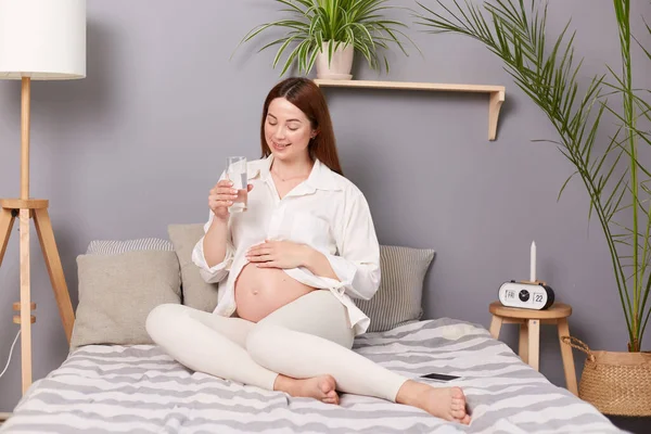 Young Pregnant Woman Drinking Water While Sitting Bed Touching Her — Stock Photo, Image