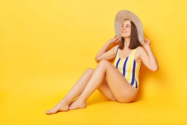 夏を楽しむ幸せを表現するビーチで黄色の背景日光浴の上に隔離された1枚の水泳スーツを身に着けている楽しいリラックスした女性 — ストック写真