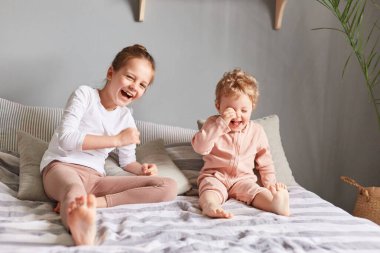 Kızlar ya da kız kardeşler yataklarında rahat rahat eğleniyorlar. Mutlu mesut gülüyorlar, kameraya bakıyorlar, hafta sonu sabahlarının tadını çıkarıyorlar..