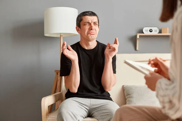 心理学センターで心理学のセッションを持っている男と女性 彼の問題について話して泣いて動揺男 専門家は彼の状態についてメモを作る — ストック写真