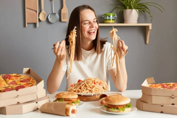 Задоволена Усміхнена Жінка Білій Сорочці Сидить Столом Нездоровою Їжею Кухні — стокове фото