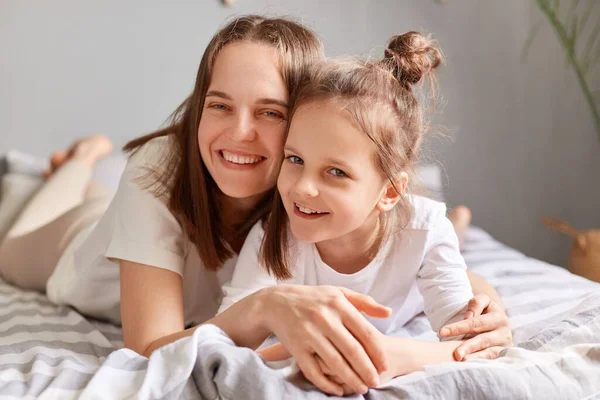 Satisfied Delighted Mother Embracing Daughter Bedroom Home Looking Camera Smiles — Stock Photo, Image
