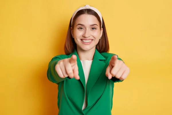 Радісна Усміхнена Жінка Зеленій Куртці Позує Ізольовано Жовтому Тлі Вказуючи — стокове фото