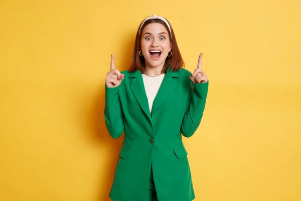 Здивована Позитивна Жінка Зеленій Куртці Стоїть Ізольовано Жовтому Тлі Вказуючи — стокове фото
