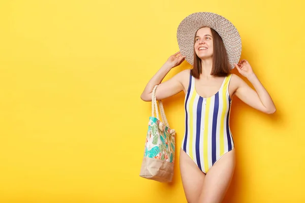 黄色の背景に隔離された水着を身に着けている楽しい魅力的な女性は離れて見て立ってプロモーションテキスト広告領域のためのコピースペース — ストック写真
