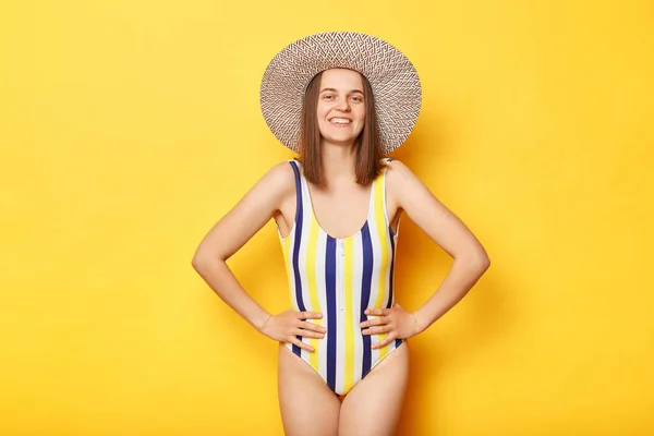 행복해 보이는 슬림은 배경에 고립된 수영복을 표정으로 카메라를 여성을 — 스톡 사진