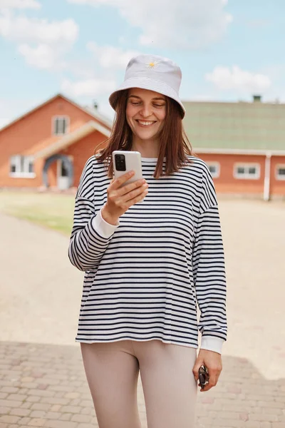 Young Smiling Woman Using Smartphone Standing Road Houses Wearing Striped — Stock Photo, Image
