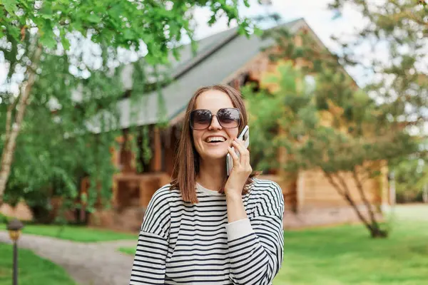 Kvinna Bär Randig Skjorta Och Solglasögon Talar Smartphone Stående Parken — Stockfoto