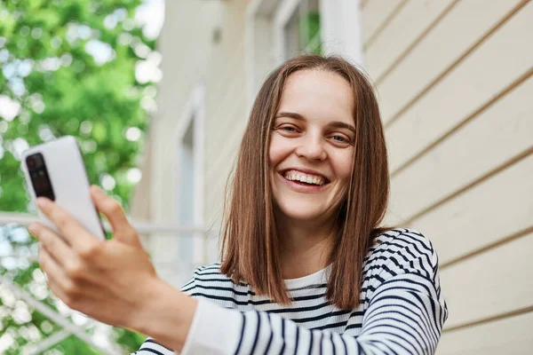 Nevető Fiatal Tartja Okostelefonját Kezében Miközben Tornácon Ház Segítségével Üzenetet — Stock Fotó