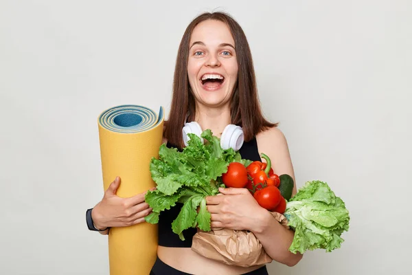 Skrattar Vit Kvinna Som Håller Yogamatta Och Organiska Grönsaker Stående — Stockfoto