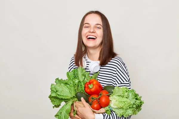 美丽的微笑的女人抱着新鲜的蔬菜 在白色的背景上显得孤立无援 看着镜头 笑容满面地呼唤着吃着有机食品 — 图库照片