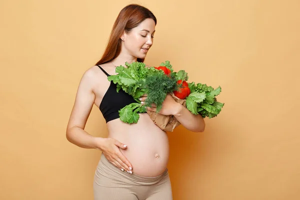 Piękna Kobieta Ciąży Gołym Brzuchem Obejmuje Patrząc Świeże Warzywa Pozowanie — Zdjęcie stockowe