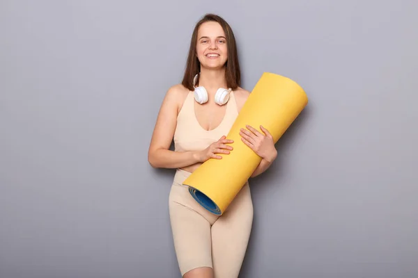Zelfverzekerde Bruinharige Vrouw Houdt Yoga Mat Geïsoleerd Grijze Achtergrond Kijken — Stockfoto