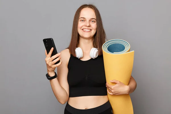 Mujer Positiva Sonriente Satisfecha Pie Llevando Estera Yoga Utilizando Teléfono — Foto de Stock