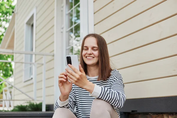 Winsome Attractive Young Woman Wearing Striped Shirt Using Phone Sitting — Stock Photo, Image