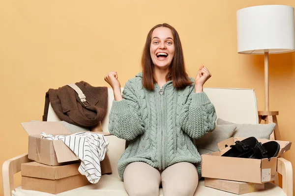 Extremely Happy Woman Sitting Sofa Boxes Clothing Beige Wall Clenched — Stock Photo, Image