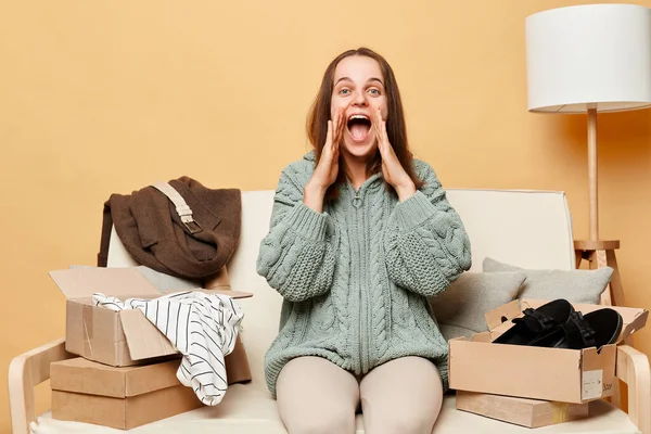 Excited Caucasian Woman Sitting Sofa Boxes Clothing Beige Wall Screaming — Stock Photo, Image