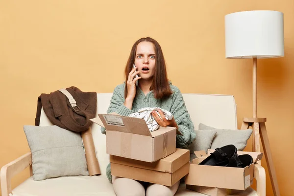 Astonished Woman Sitting Sofa Boxes Clothing Beige Wall Opening Cardboard — Stock Photo, Image