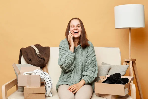 Attractive Laughing Woman Sitting Sofa Boxes Clothing Beige Wall Talking — Stock Photo, Image