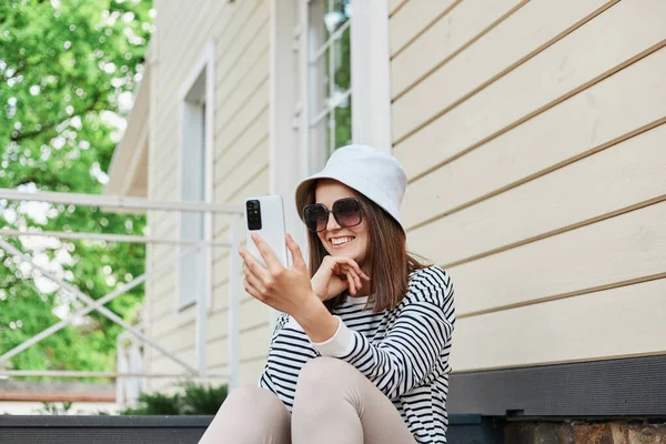 Şatafatlı Genç Beyaz Çizgili Tişört Giyen Akıllı Telefon Kullanan Verandada — Stok fotoğraf