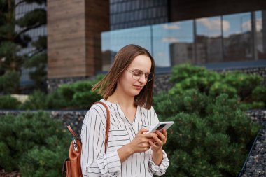 Sakin, yönetici, takım elbiseli, açık havada yürüyen, cep telefonu uygulamalarını kullanan, akıllı telefondan haber okuyan, işe giderken....