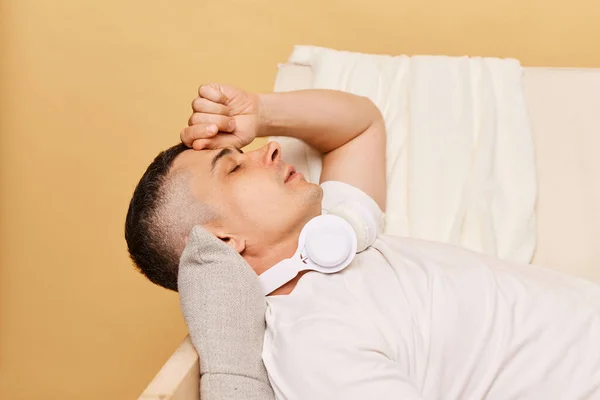 成年人躺在沙发上 背负着米黄色的背景 头疼或有各种症状 疲惫不堪 容易感觉到压力和疲劳 — 图库照片