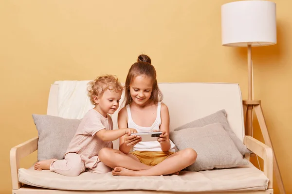 Positive Playful Little Girls Sisters Sitting Couch Using Smartphone Together — Stock Photo, Image