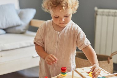 Bilişsel gelişim bulmacaları. Montessori öğrenme yaklaşımı. Ahşap inşaat seti. Küçük sarışın kız. Evinde ahşap oyuncaklarla oynaşıyor.