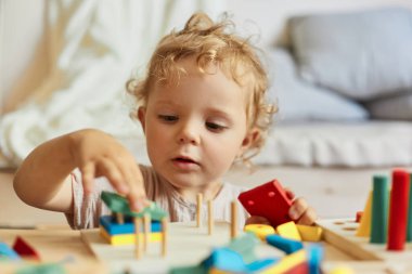 Etkileşimli eğitim oyuncakları. Eğlenceli eğitici oyunlar. Aktif çocuk oyunu. Küçük sarışın kız. Evinde ahşap oyuncaklarla oynaşıyor..
