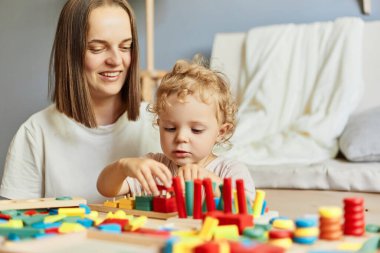 Eğlenceli çocuk yuvası aktiviteleri. Eğitici oyun odası kurulumu. Bebeklerin yaratıcı oyunu. Yaratıcı sanat seansları. Öğretmen ya da anne evde mantık oyuncaklarıyla oynuyor..