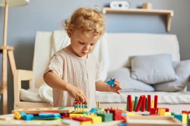 Yaratıcı sanat projeleri. Bilişsel beceri gelişimi. Montessori öğrenme materyalleri. Aktif oyun zamanı eğlencesi. Küçük sarışın kız. Evinde ahşap oyuncaklarla oynaşıyor..